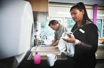 Clean, dishes and kitchen with a woman cleaning while working as a volunteer for charity, relief and humanitarian aid. Community, social worker and activism in a learning and development center