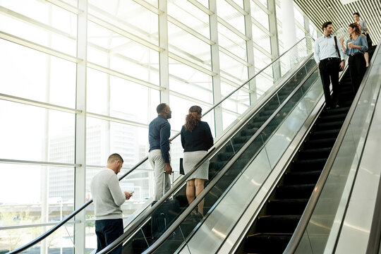 Business, people and travel on escalator at airport for conference trip, flight arrival or international expo. Professional, group and luggage on moving staircase for corporate journey or departure