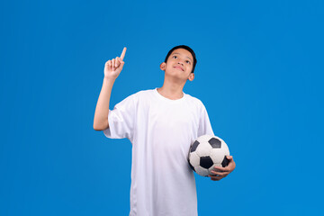 Teenage boy with soccer ball pointing at something on blue background