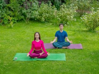 man and woman doing yoga meditating in the garden