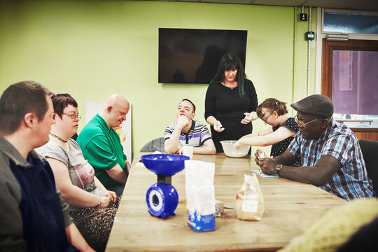 Healthcare, disability and development training with special needs group learning independence skills with a female teacher. Diverse real people with different handicap in a mobility testing facility