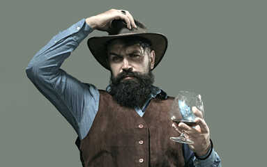 Cognac glass held by bearded man. Guy drinking cognac alone at bar. Whiskey cognac in classic...