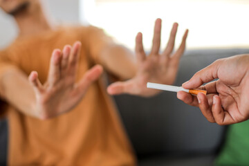 Close up hands of a man refusing to smoke cigarette.
