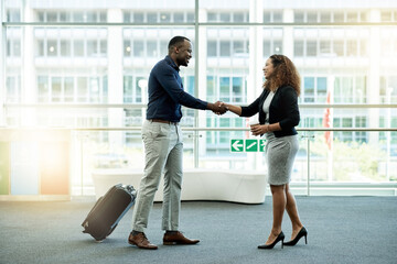 Handshake, luggage and welcome with business people in airport lobby for friendly greeting or meeting. B2B, smile or travel with employee man and woman shaking hands for international partnership