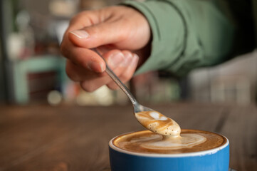 Close up of someone scooping creamy surface of hot latte coffee.