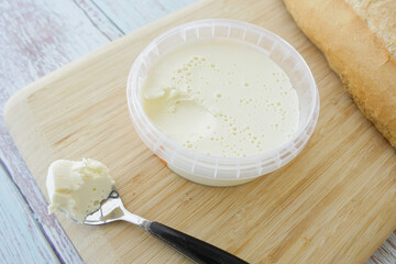 Creamy spread on a wooden board next to fresh bread