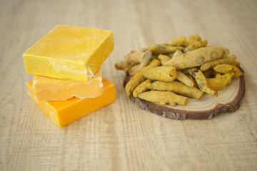 Colorful handmade soaps and natural turmeric roots on wooden table