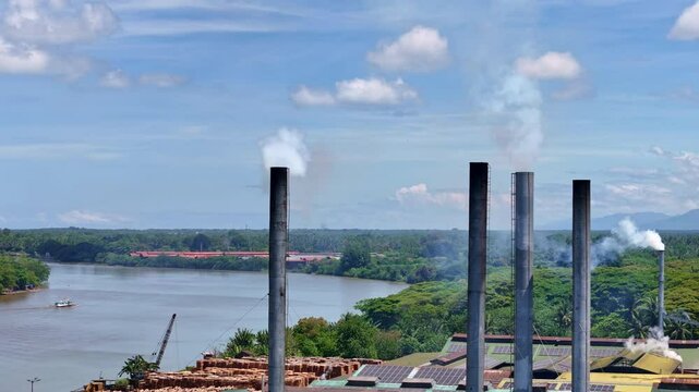 Industrial plywood factory smokestacks pump black smoke into the air, polluting the rural landscape of Butuan in Agusan Del Norte, Mindanao, Philippines.