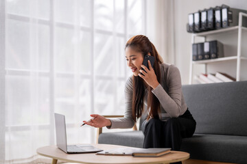 A woman is sitting on a couch and talking on her cell phone