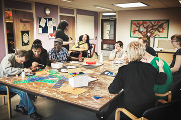 Painting, learning and disability with a volunteer, charity or social worker working with a patient...
