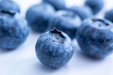 A cluster of blueberries, sits on a soft white surface, emphasizing freshness and texture.