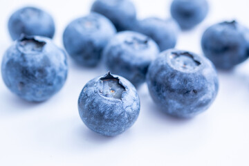 A cluster of blueberries, sits on a soft white surface, emphasizing freshness and texture.