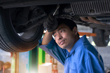 The technician was exhausted and wiped his sweat with his forearm as he inspected under the lifted vehicle.