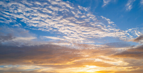 Fototapeta premium Sky at sunset. Sunrise over horizon. Sunset through clouds on sky. Twilight sky with sunset colors. Peaceful dawn with soft light. Dramatic dusk sunset with clouds. Sunshine in clear sky.