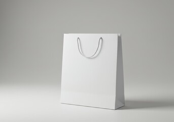 A simple white shopping bag with rope handles on a white surface against a light gray background