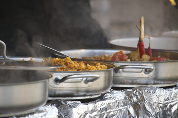 A variety of flavorful foods in stainless steel pans are steaming, creating an inviting culinary display.