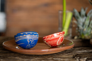 Clay copitas resting on rustic ceramic plate, traditional mezcal drinking vessels waiting for...