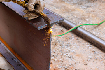 Welder uses torch to cutting metal plates, producing bright sparks on construction site