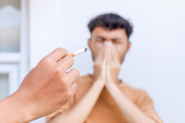 Passive smoking concept. Young man covering face from cigarette smoke