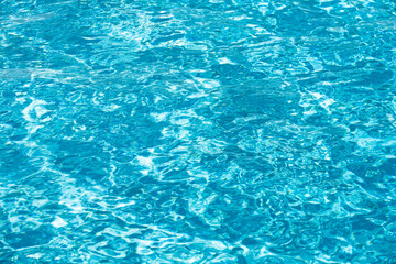 Water background. Blue water, ripples and highlights. Texture of water surface and tiled bottom.