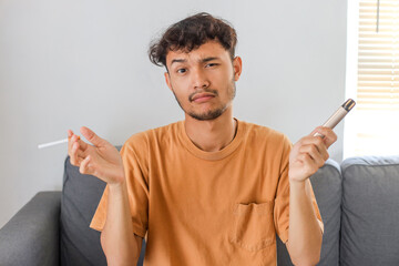 Confused Asian guy holding cigarette and vape, hard to choose