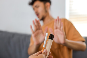 Hand holding out cigarette and vape, offering a man but he refuses
