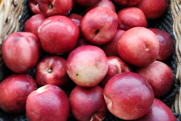Large group of fresh red plum nectarine in basket on display in the supermarket or grocerie store, close up photo