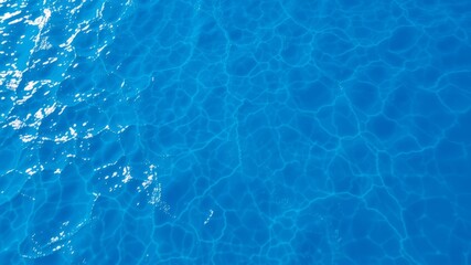 Obraz premium A high-angle shot depicts a tranquil ocean surface with subtle ripples and glistening sunlight reflecting on the deep blue water.