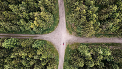 Aerial drone view of dirt road junction in green forest, top view of nature landscape and roads intersection from above, forest background