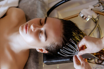 Close-up of a woman relaxing during a Japanese head spa treatment at a beauty salon. Scalp massage with a tool designed to promote relaxation, reduce stress, and improve scalp circulation for hair