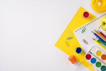 Colorful school essentials arranged creatively on a vibrant yellow surface, ideal for...