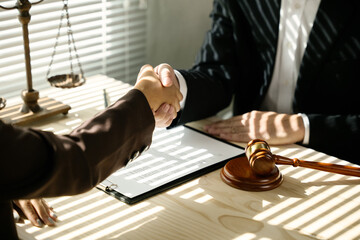 Close up of hands Lawyers explain and discuss matters of law then shakehands after and dealing contract agreement to clients discuss for prepare for the trial. gavel hammer and scales of justice.