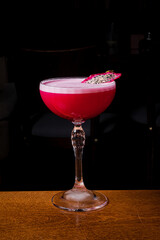 A vibrant dragon fruit cocktail gleams in a glass against a dark backdrop