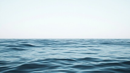 Calm ocean waves meet a pale sky