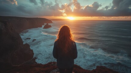 A rocky coastline with crashing waves and a dramatic sky filled with clouds at sunset