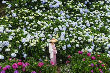 Beautiful pregnant woman in hydrangea flower garden