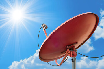 Satellite dish antenna against a clear blue sky with sunlight and clouds