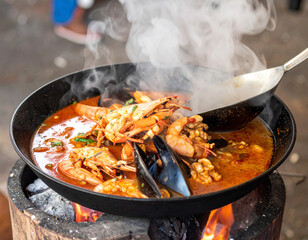 A steaming bowl of curanto, a traditional Chilean seafood and meat stew cooked in a pit, showcasing a unique Patagonian culinary tradition.