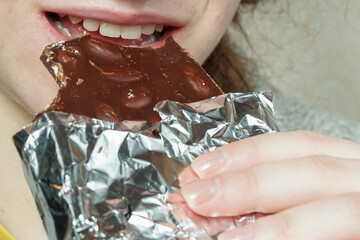 Bar of chocolate and teeth of a young girl. Eating chocolate close up.