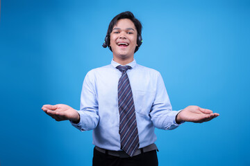 Smiling operator man with headset spreading arms consulting clients online against blue background