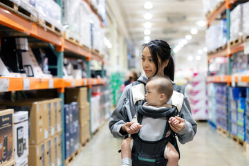 Mother shopping with baby in supermarket aisle