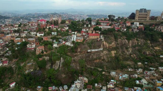Slow backward aerial movement revealing the Antananarivo hillside sign, the historic Queen&rsquo;s Palace (Rova Manjakamiadana), and the sprawling cityscape of Madagascar.