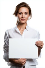 Naklejka premium A woman is holding a white sign. She is smiling and looking at the camera. The sign is blank, which could represent a blank slate or a new beginning