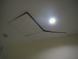 Ceiling with visible crack and recessed light fixture, indicating potential structural issues....