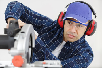 serious worker cutting metal bar with circular saw