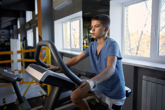 Teenage boy enjoying physical exercise training on mechanical elliptical trainer