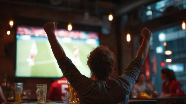 Victory Celebration at the Pub: A lone spectator celebrates a goal, arms raised in triumph, silhouetted against a large screen displaying a soccer match in a lively pub atmosphere.