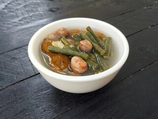 Sayur asem or Vegetables soup in bowl on black wooden table background. Indonesian typical food