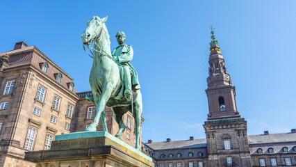 Obraz premium Equestrian statue of Christian IX stands prominently outside Christiansborg Palace in Copenhagen, Denmark. The statue showcases historical significance and architecture of the area.