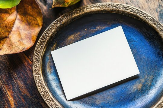 Blank business card on an ornate plate surrounded by autumn leaves, showcasing simplicity - Powered by Adobe